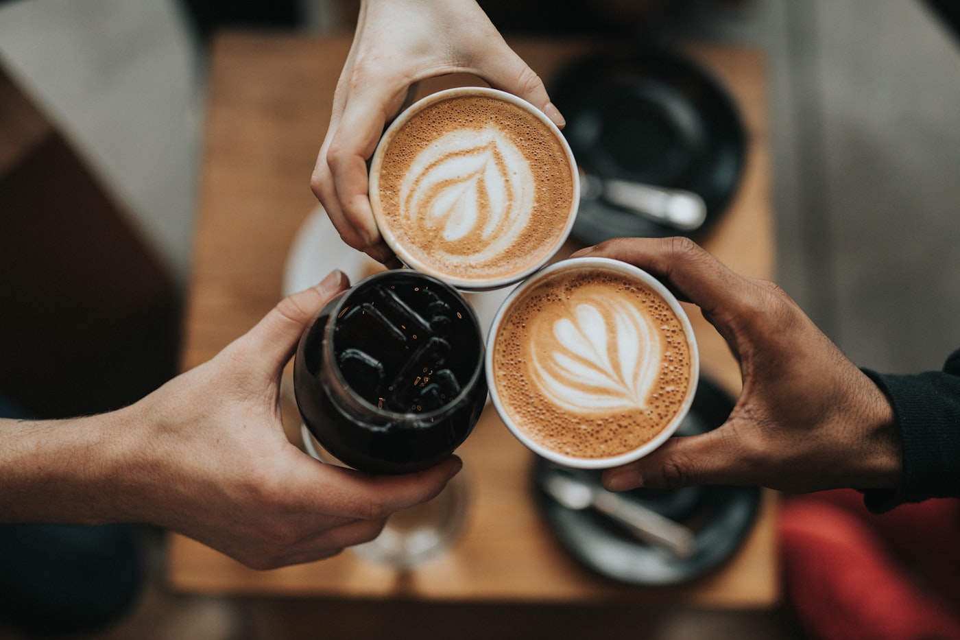 Taza de café con arte latte sobre una mesa de madera junto a granos