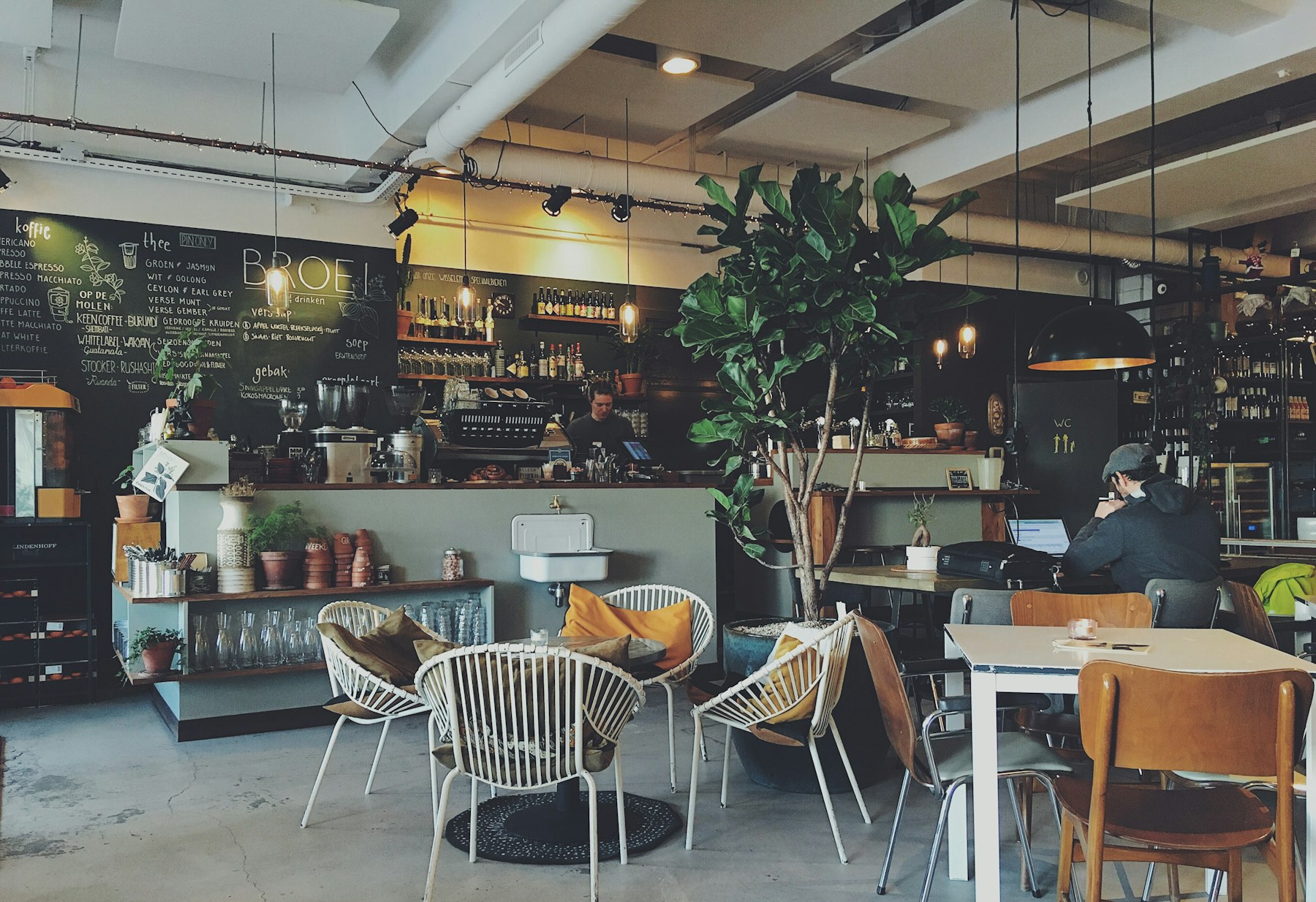 Salón de la cafetería con sillones de cuero, mesas de madera y ventanales al cerro
